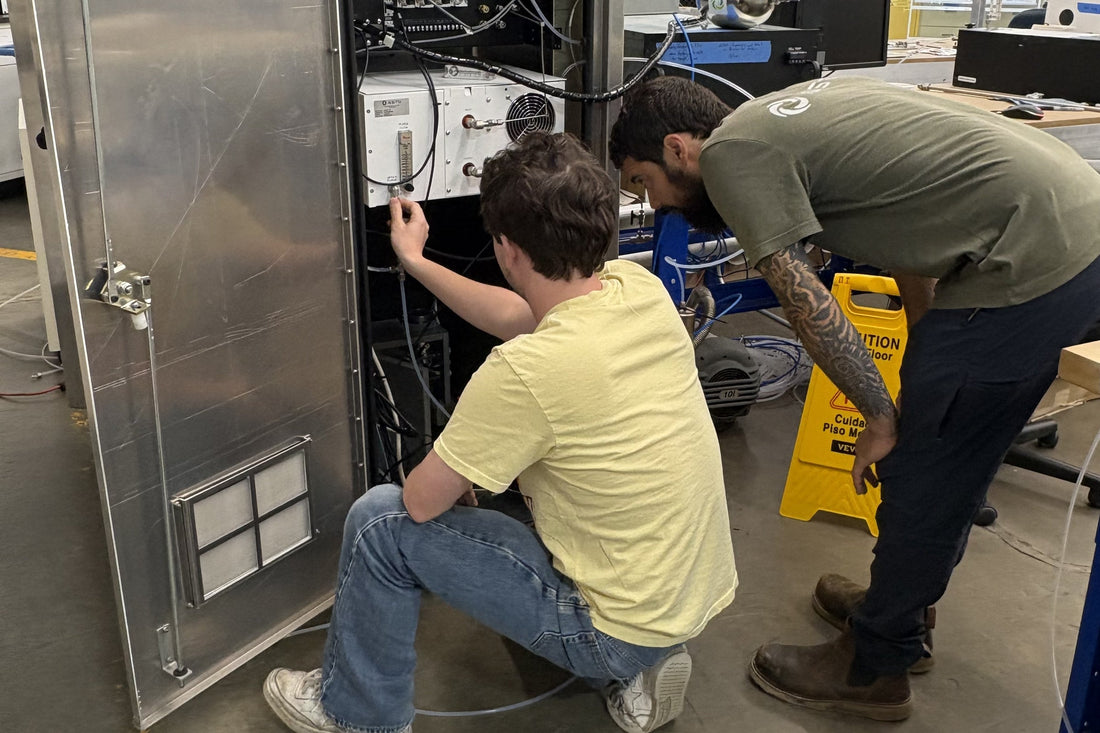 Two ASTG technicians working inside an analyzer cabinet during system build and checkout at the Newton, New Jersey facility