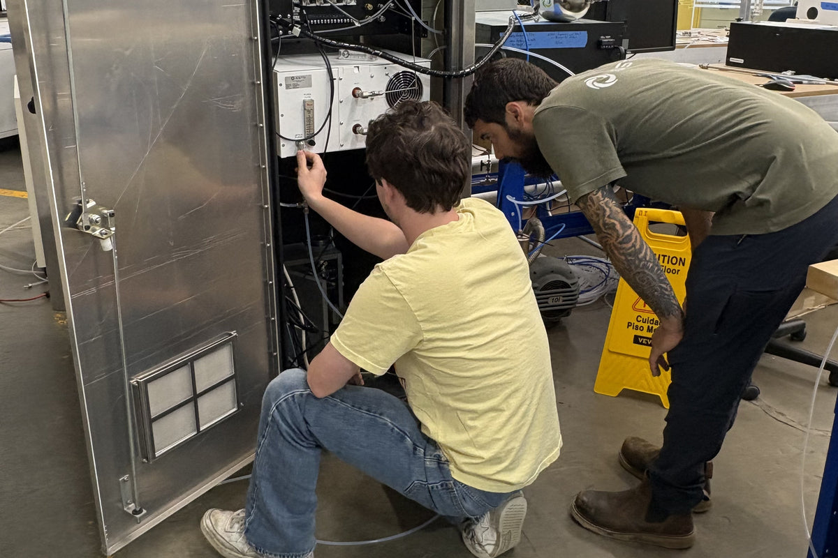 Two ASTG technicians working inside an analyzer cabinet during system build and checkout at the Newton, New Jersey facility