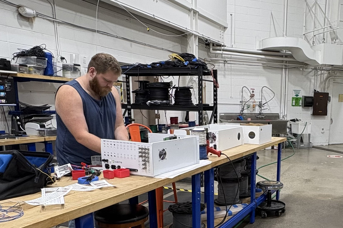 ASTG technician assembling analyzer enclosure panels at a wiring bench in the Newton, New Jersey facility