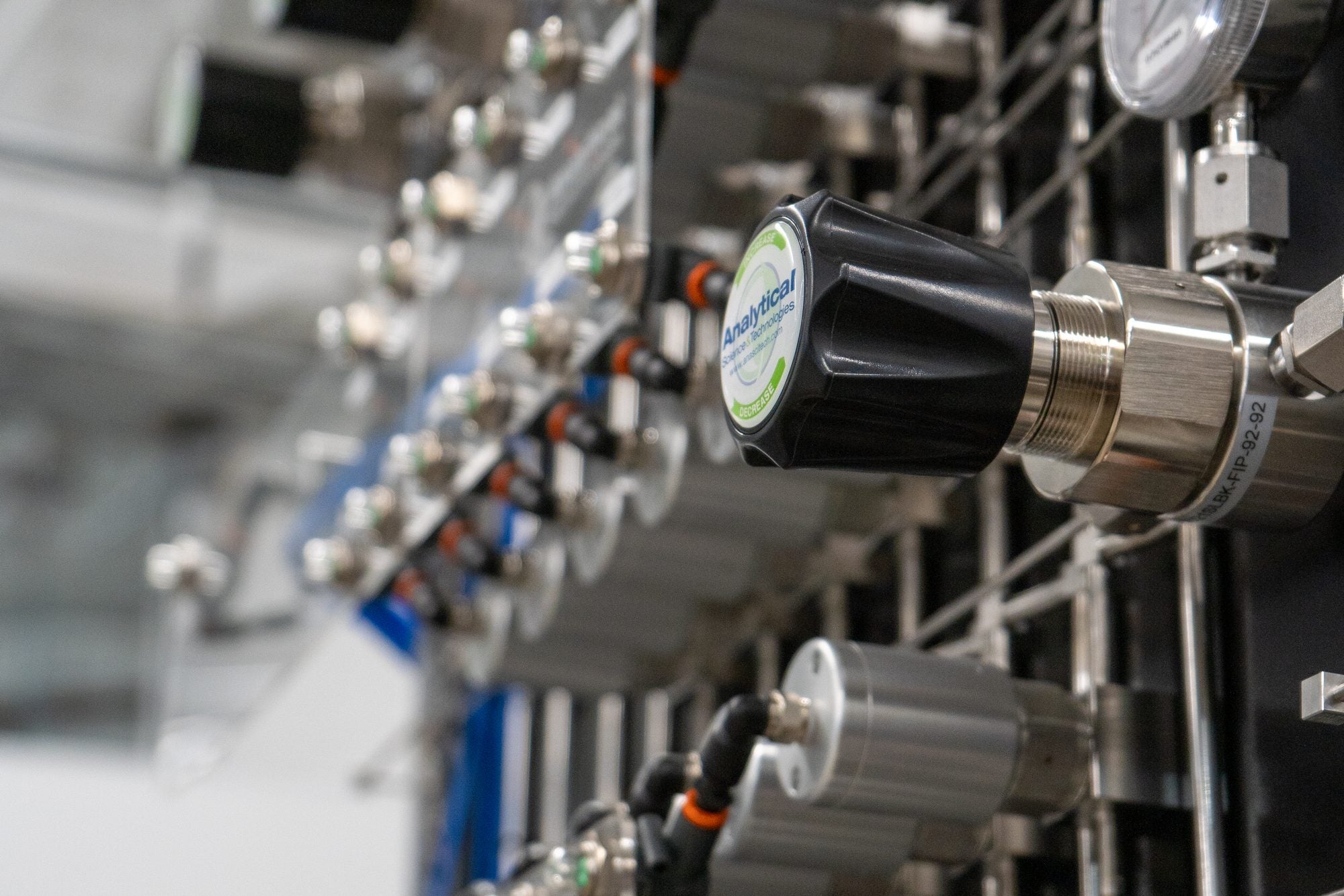Rack of gas regulators, pressure gauges and stainless steel tubing on an ASTG analytical system