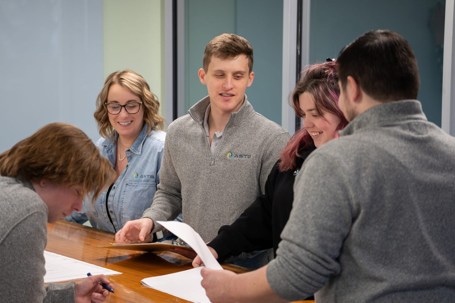 The ASTG team working together around a table at the Newton, New Jersey headquarters